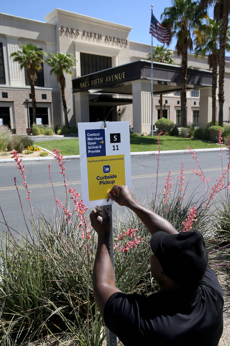 A worker who declined to give his name installs Curbside Pickup signs at the Fashion Show Mall ...